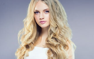 Beautiful blonde girl with long curly hair over purple backgroun