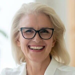 Headshot portrait of happy aged grey-haired businesswoman in glasses look at camera with toothy wide smile, close up of overjoyed senior woman boss or ceo in spectacles posing for picture