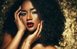 Beauty photo of young elegant african american woman with afro hair. Glamour makeup. Golden Background. Studio shot.